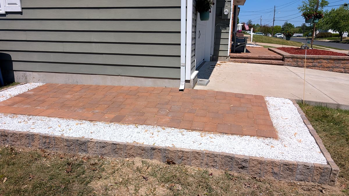 After: close view of the finished trash-can paver pad and stone border