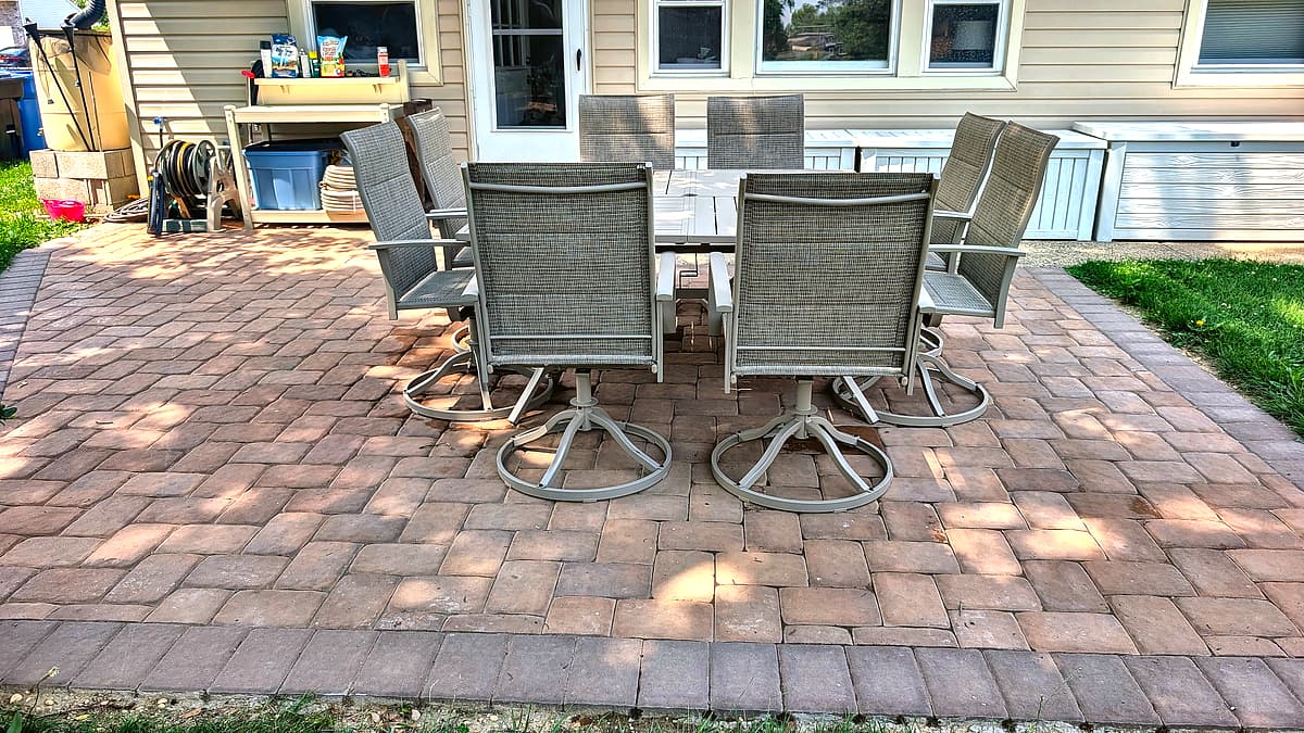 Paver patio with eight-seat outdoor table set against the back of the house